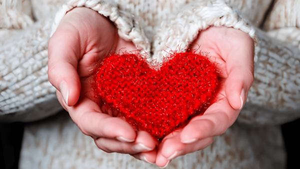 coração renovado -Mãos de uma pessoa segurando um coração vermelho de tecido, simbolizando amor, cuidado, renovação e transformação interior.