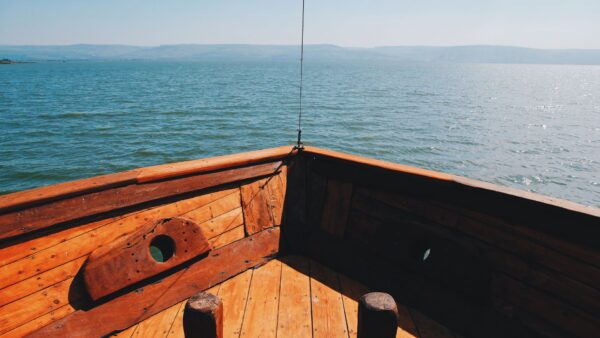 Visão da proa de um barco, tendo o horizonte infinito do oceano.