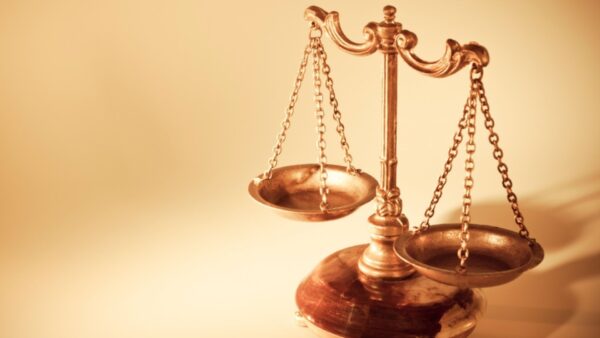 Uma balança da justiça em tons dourados sobre fundo claro, simbolizando equilíbrio, direito, ética, moralidade e a busca pela equidade.