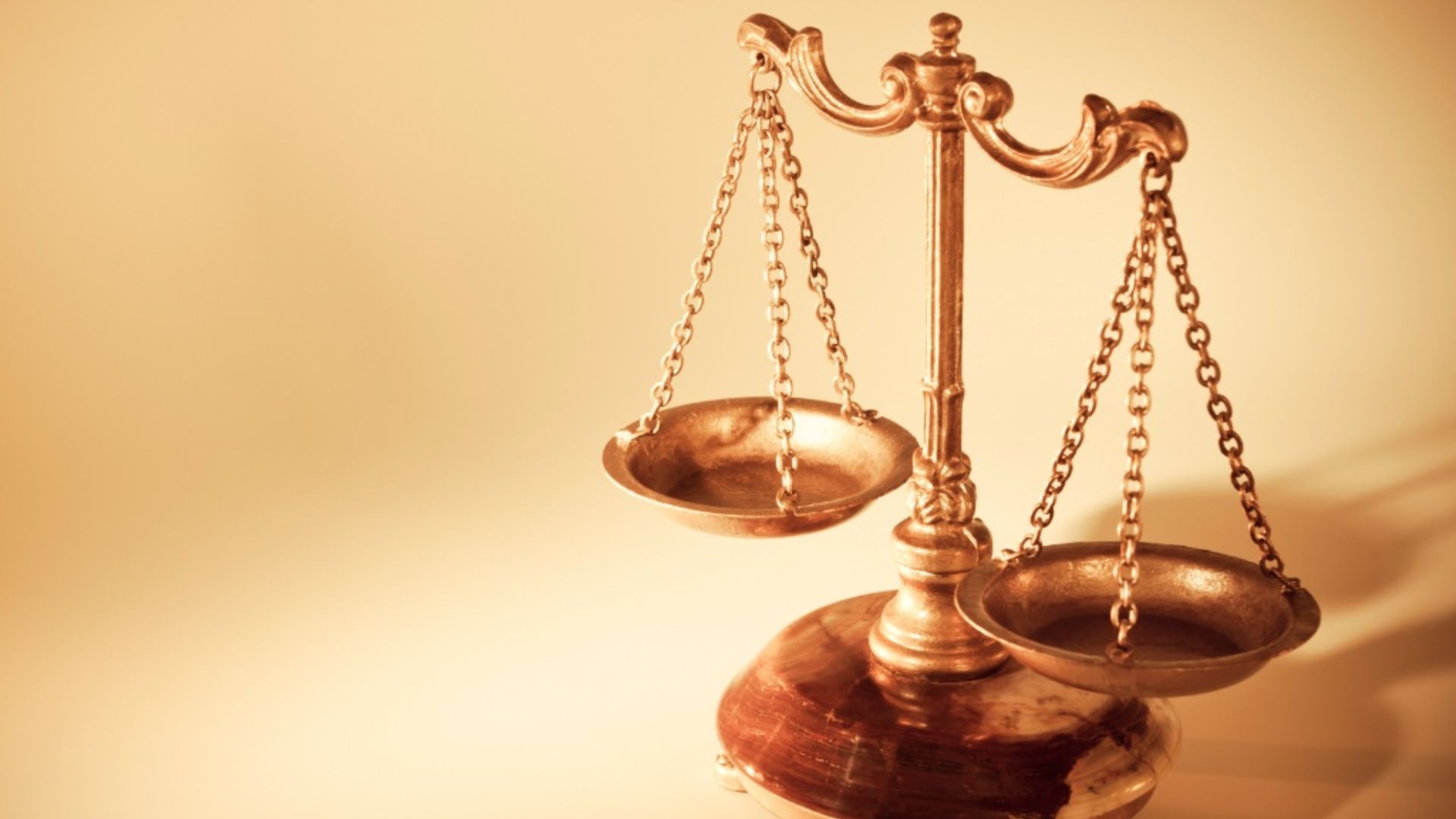 Uma balança da justiça em tons dourados sobre fundo claro, simbolizando equilíbrio, direito, ética, moralidade e a busca pela equidade.