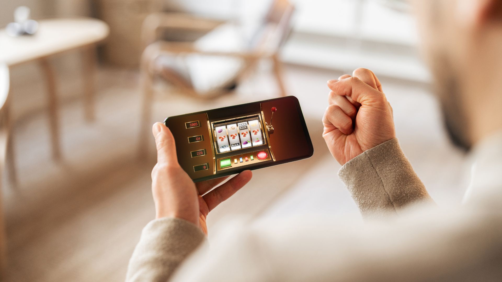 Pessoa segurando um celular com um jogo de apostas, representando a prática de jogos de azar pelo celular.