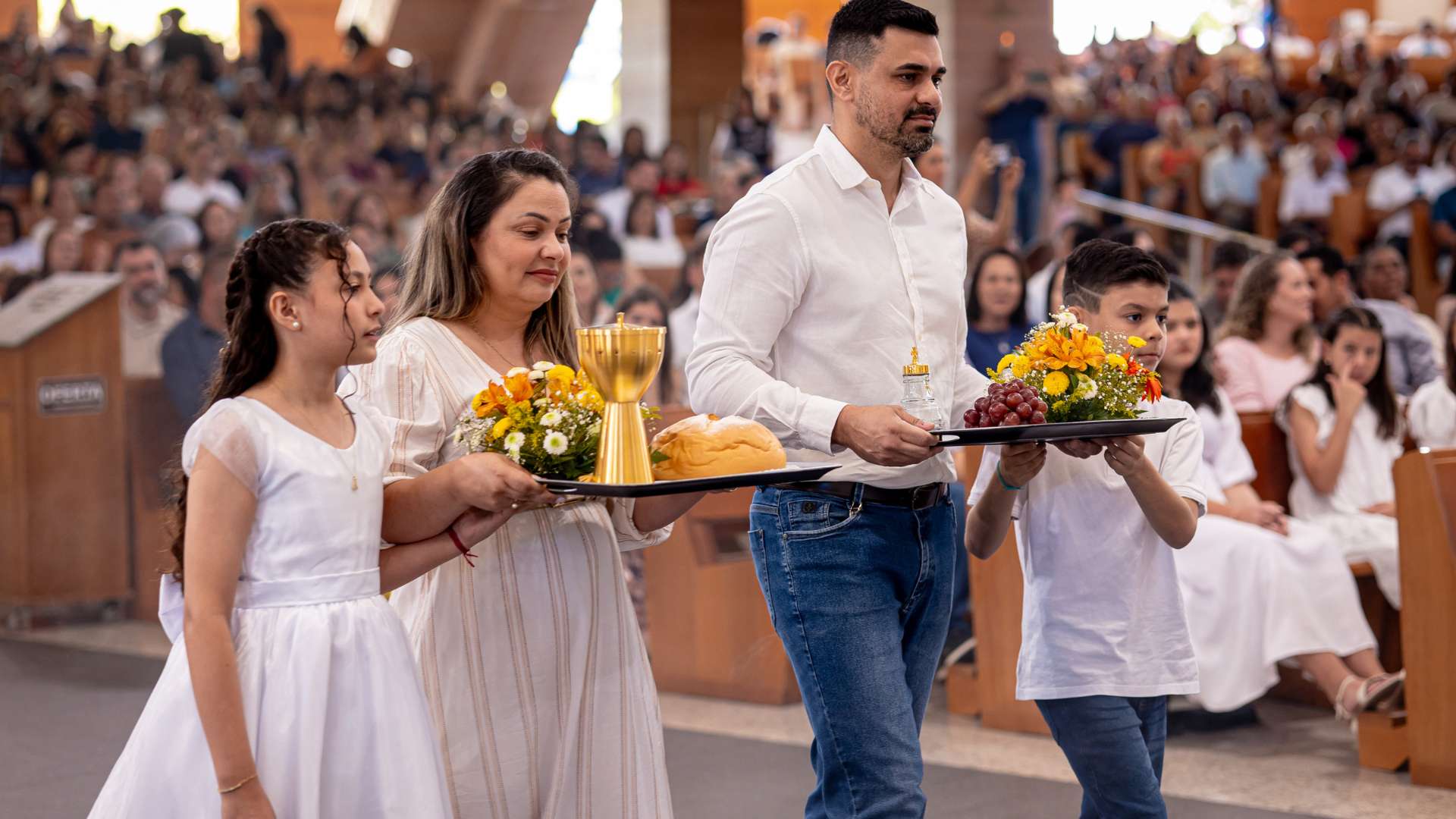 Pais trazem ofertas de pão e vinho para o altar na missa. 