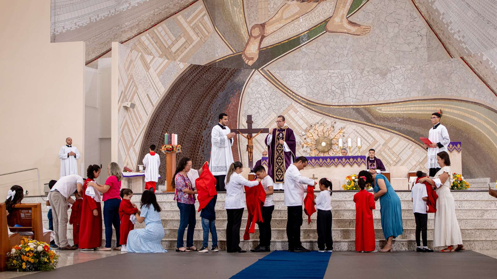 Pais colocam as veste de novos coroinhas nas crianças. 