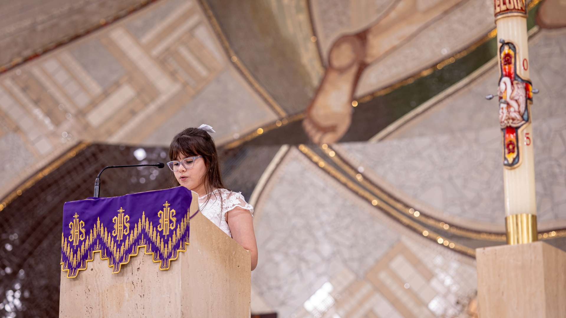 criança faz leitura durante missa da primeira eucaristia no santuário do Pai das Misericórdias 2025. 