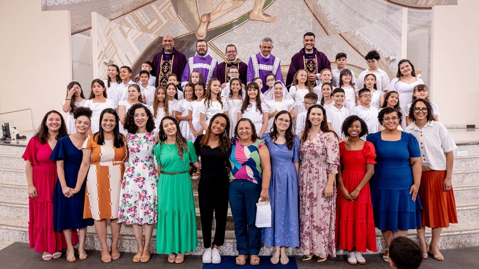 Crianças do Instituto Canção Nova em suas vestes brancas durante a Missa de Primeira Eucaristia no Santuário do Pai das Misericórdias, com as mãos sobre o peito em oração.