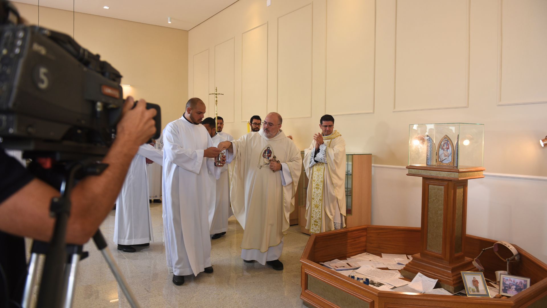 Padre joga água benta na nova sal das graças com sacerdotes ao redor